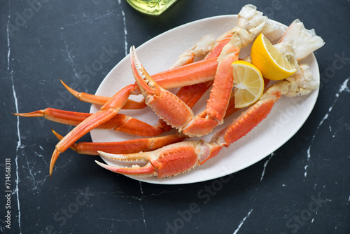Plate with boiled opilio or snow crab on a black marble background, horizontal shot, high angle view