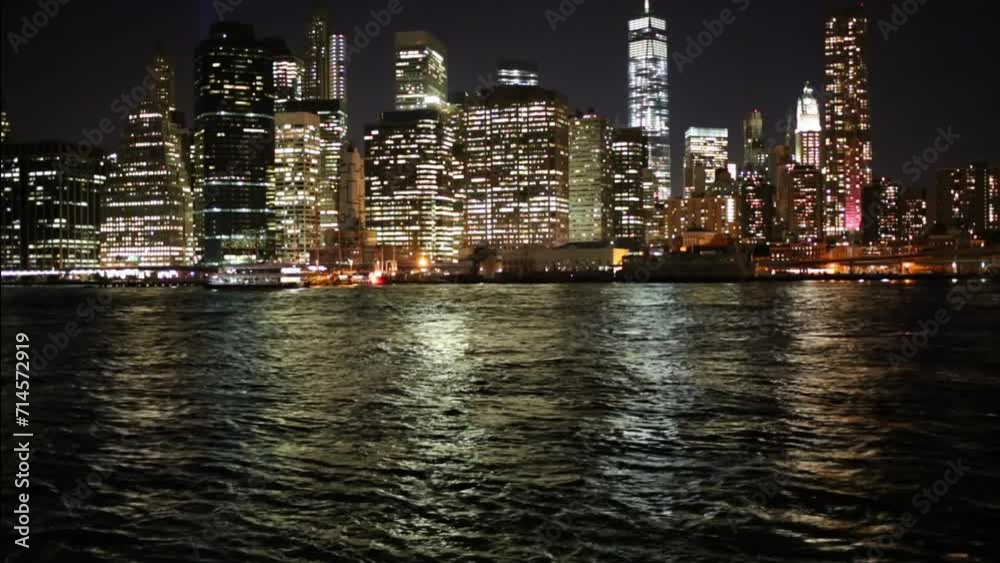 Skyscrapers near river in New York city and moving ship at night Skyscrapers near river in New York city and moving ship at night