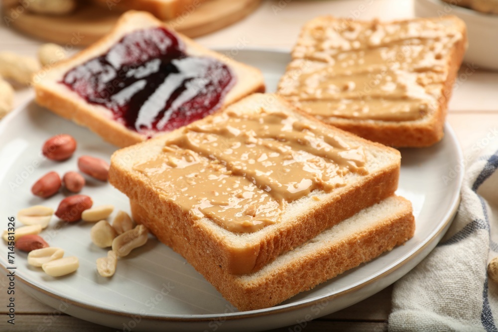 Delicious toasts with peanut butter, jam and nuts on table, closeup Delicious toasts with peanut butter, jam and nuts on table, closeup