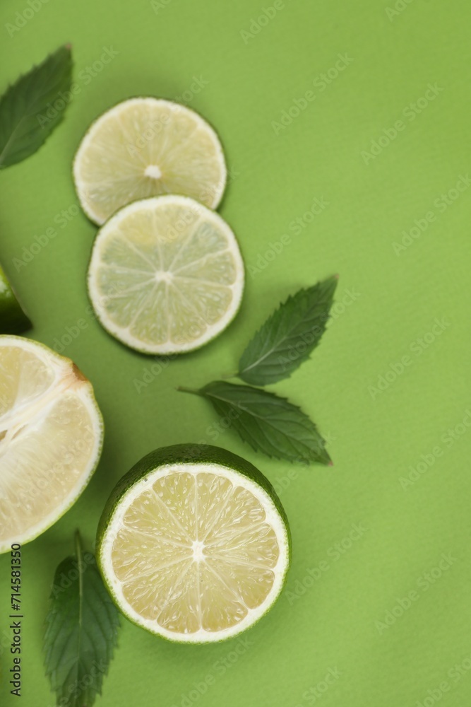 Flat lay composition with fresh limes and leaves on green background Flat lay composition with fresh limes and leaves on green background