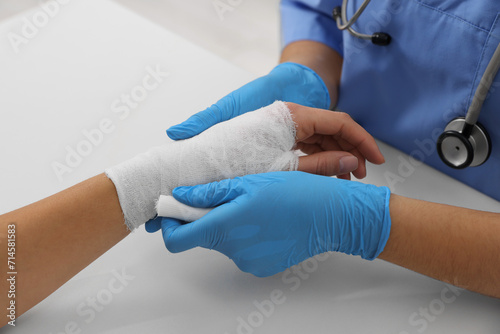 Doctor bandaging patient's burned hand at table, closeup