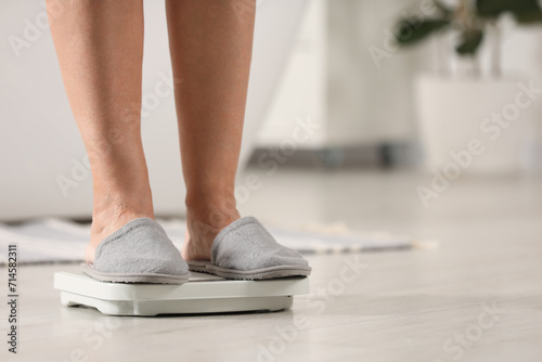 Menopause, weight gain. Woman standing on floor scales indoors, closeup. Space for text