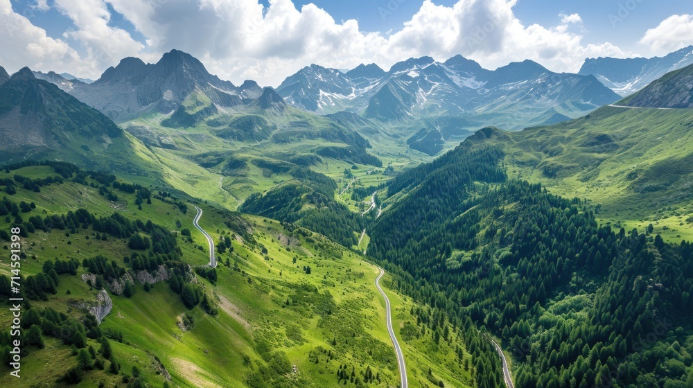 Obraz premium a scenic view of a mountain range with a winding road in the foreground and a winding road in the middle of the mountain range on a sunny day with white clouds in the sky.