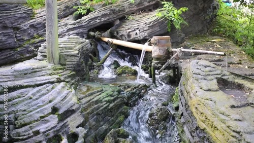 Stream among grey rocks with drum and trough at summer