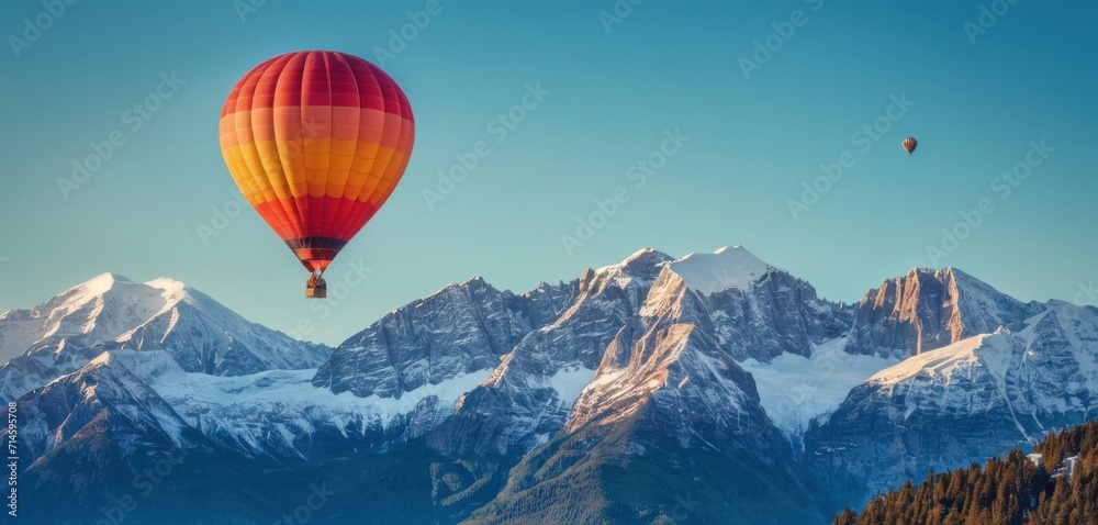  a red and yellow hot air balloon flying in the sky over a mountain range with snow covered mountains in the background and a blue sky with two hot air balloons in the foreground.