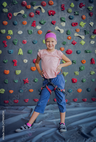 A strong baby climber posing for photographer at artificial wall.
