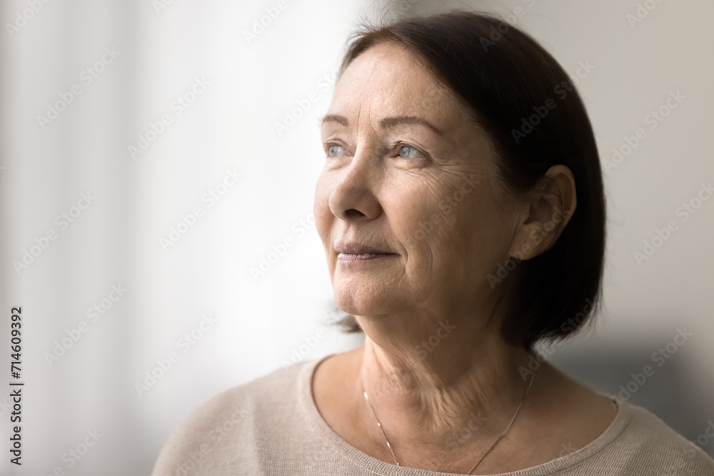 Fototapeta premium Serious pensive senior woman close up casual portrait with copy space. Thoughtful face of elderly female model looking at window away, daydreaming, thinking, pondering
