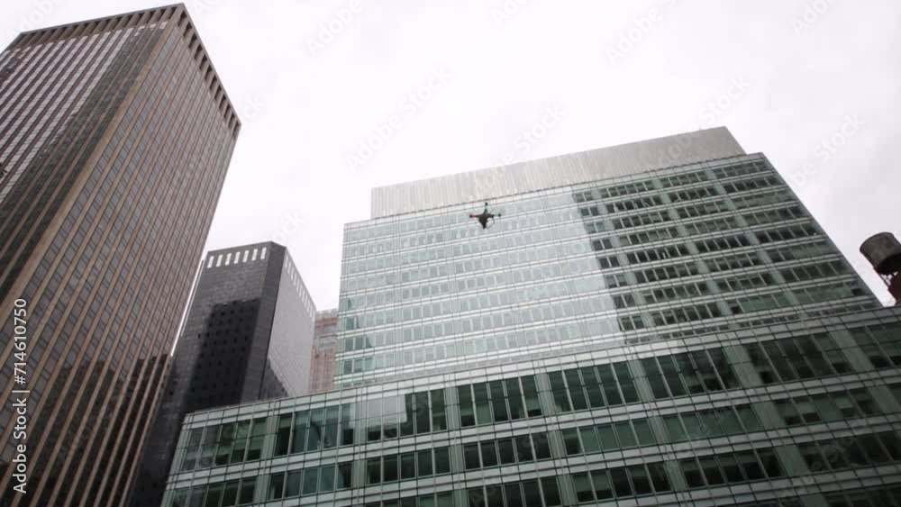 Man remote controls quadrocopter among glass skyscrapers Man remote controls quadrocopter among glass skyscrapers