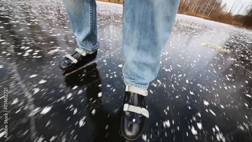 Legs of man in jeans skating on frozen pond among trees photo