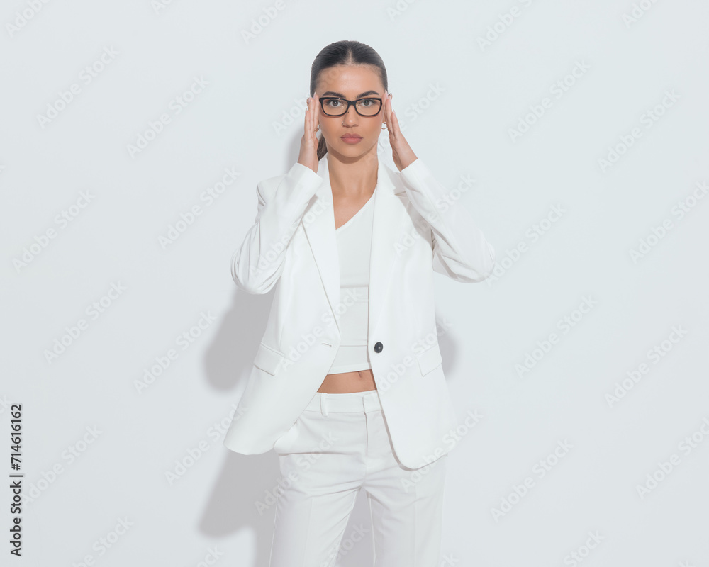 attractive young woman fixing glasses and looking forward while posing