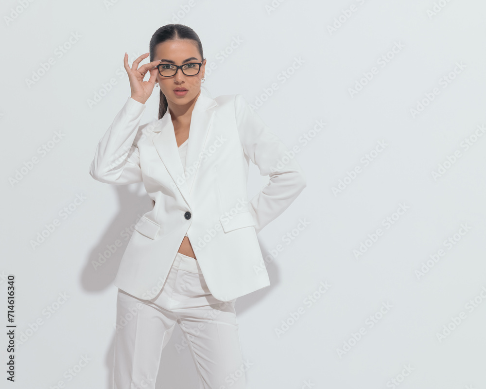 sexy fashion woman in white suit looking forward and adjusting eyeglasses sexy fashion woman in white suit looking forward and adjusting eyeglasses