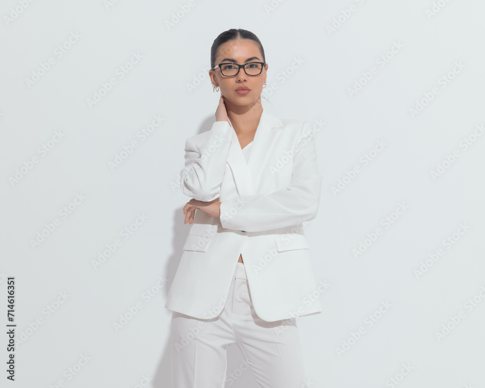 attractive young woman with glasses in white suit holding hand on neck attractive young woman with glasses in white suit holding hand on neck