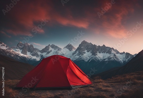 Glowing red tent camping in the mountains in front of majestic mountain range