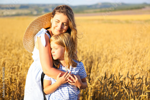 Mother and baby daughter hugging in the wheat field photo