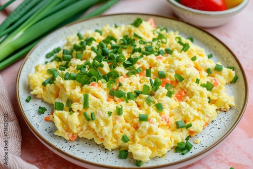 Scramble with green onions on a plate, peach pastel background