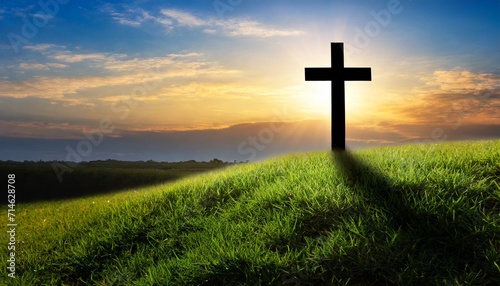 silhouette christian cross on grass in sunrise