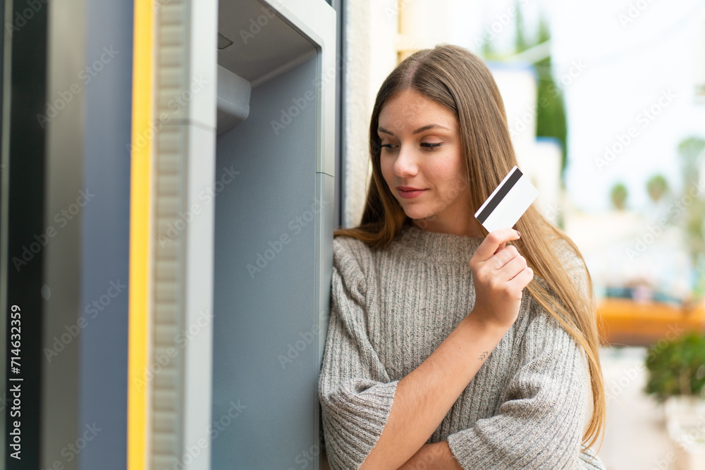 Young pretty blonde woman using an ATM