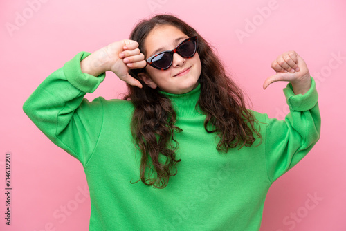Little caucasian girl wearing sunglasses isolated on pink background proud and self-satisfied