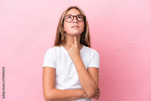 Little caucasian girl isolated on pink background With glasses and looking up