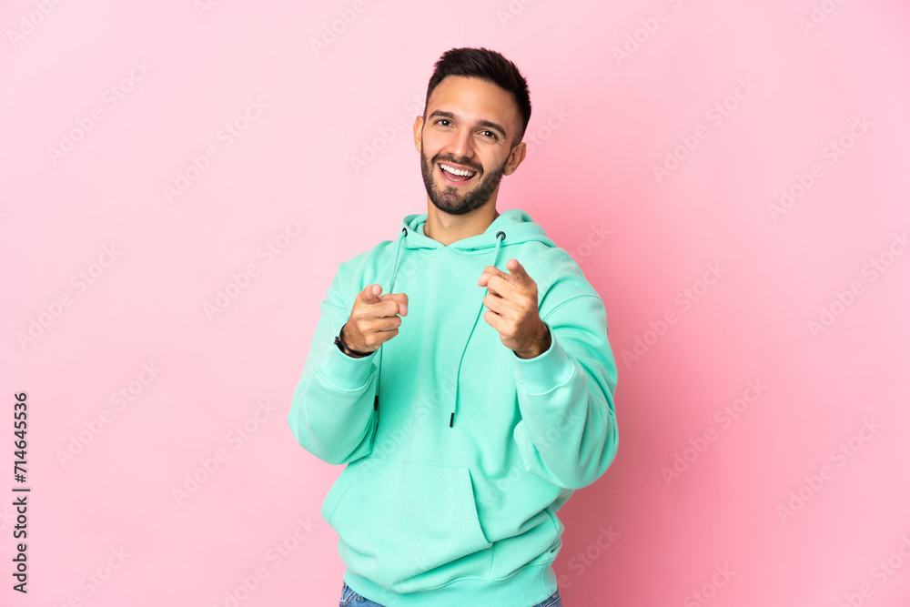 Young caucasian man isolated on pink background surprised and pointing front Young caucasian man isolated on pink background surprised and pointing front
