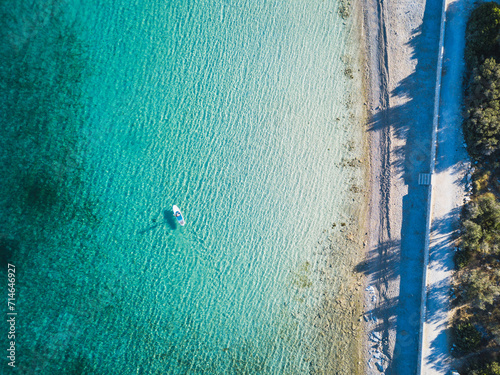 Aerial drone top down photo of young woman on Stand Up Paddle Board, SUP in turquoise clear sandy beach in mediterranean sea