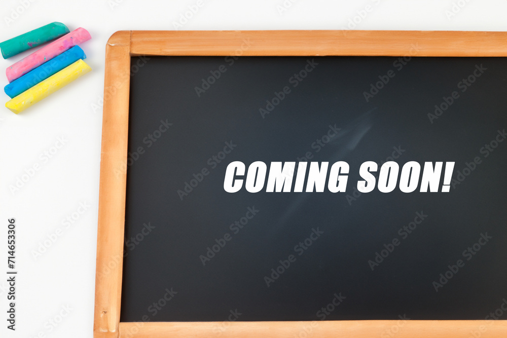 drawing composition. on a white table there is a board with the inscription soon, colored crayons lie next to it