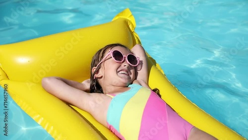 Cute little girl lying on inflatable mattress in swimming pool with blue water on warm summer day on tropical vacations. Summertime activities concept. Cute little girl sunbathing on air mattress