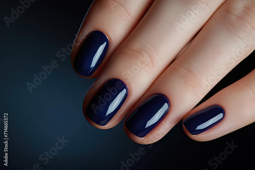 Close-up of woman fingers with beautiful navy blue manicure. Pastel color nail manicure with gel polish at luxury beauty salon.