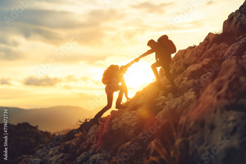 Concept of teamwork – silhouettes of two people climbing on mountain and helping each other out