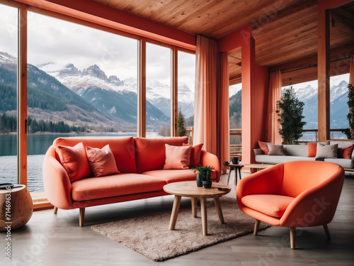 Coral color sofa and armchair against window with river and mountain view. Scandinavian home interior design of modern living room in chalet 
