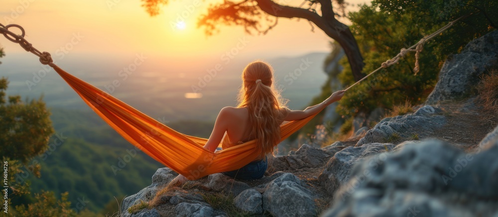 Young woman relaxing in hammock on top of the mountain at sunrise