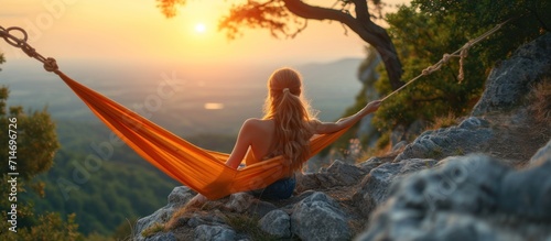Young woman relaxing in hammock on top of the mountain at sunrise