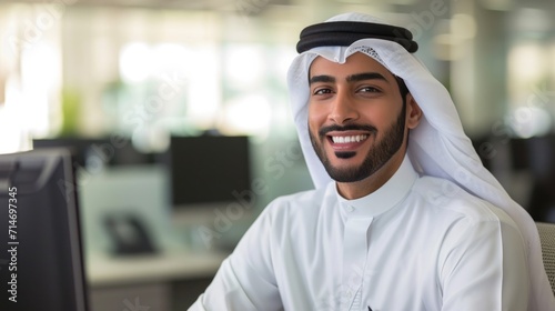 Happy Emirati Arab at office wearing kandura looking at front ideal for Middle East business concept .