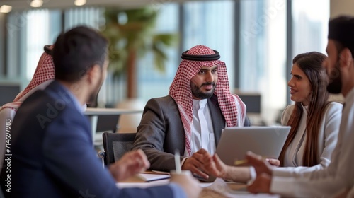 International Business Consultant Advises on Financial Strategy Plan to Successful Arab Company Owners. Multicultural Meeting in Modern Office Between American and Saudi Businessman. photo