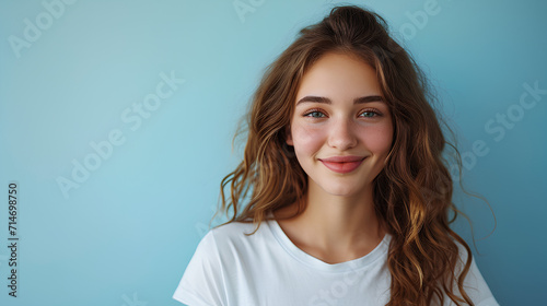 Smiling Young Woman in White Short Sleeve T-Shirt on Light Blue Background with Empty Space © Lumina