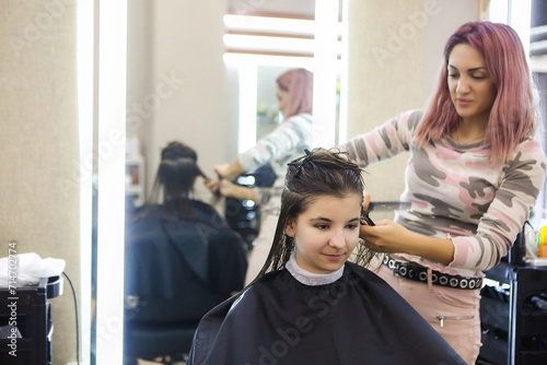 Female hairdresser cutting hair of cheerful woman