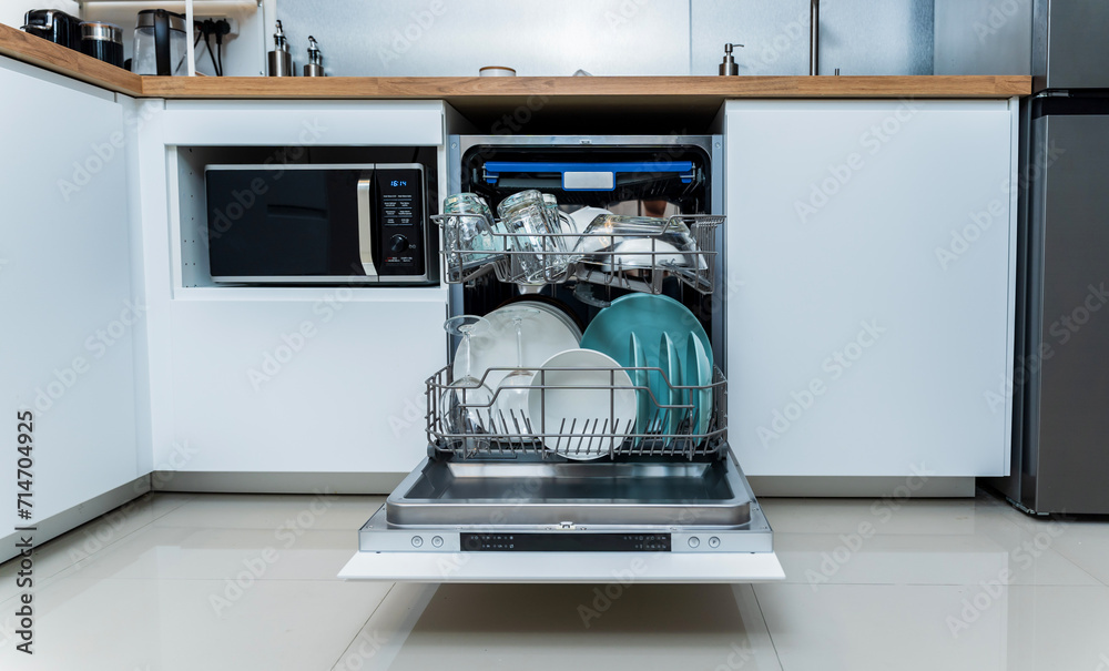 The white kitchen and opened dishwasher with clean dishes The white kitchen and opened dishwasher with clean dishes