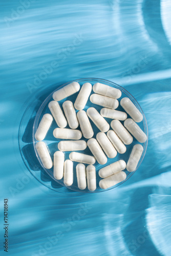 White medicinal capsules, vitamins or dietary supplements in close-up on a blue background. Medicine