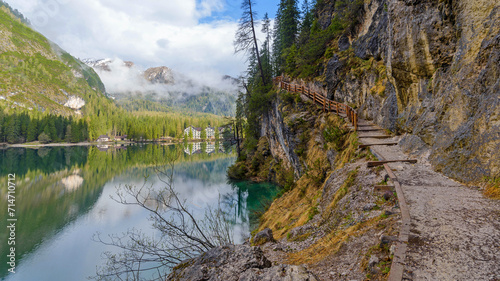 panoramic landscape of mountain lake Braies in the Dolomites, Italy. Hiking trail along the lake and low clouds over the mountain