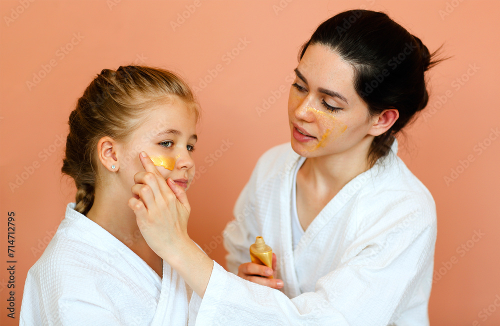 Family spa day. Young mother and little daughter in bathrobes doing beauty treatment together Family spa day. Young mother and little daughter in bathrobes doing beauty treatment together