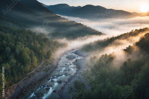 River located in the middle of a misty mountain forest at sunrise from a drone's point of view