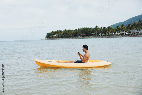Joyful Asian Man on a Kayak, Enjoying a Tropical Beach Vacation
