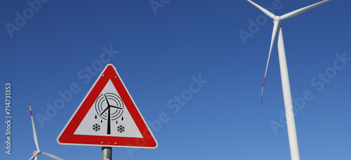 Photography a sign on a wind turbine with the text caution icefall, danger to life