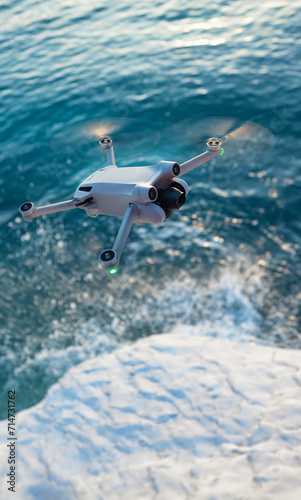 A quadcopter in flight against the background of a beautiful sea and white cliffs in the sunset light