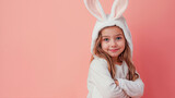 Petite fille souriante, les bras croisés, avec un costume de lapin blanc - fond rose