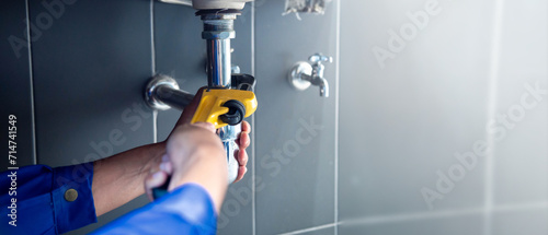 Plumber fixing white sink pipe with adjustable wrench. photo