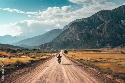 Aeriel view of a man riding a motorcycle bike on a mountainous valley road © DailyLifeImages