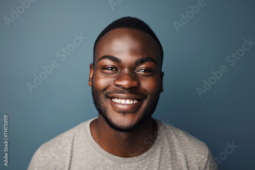 A man in a grey shirt smiles for the camera