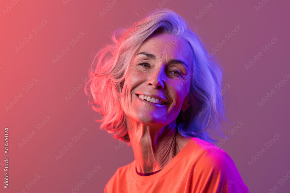 A woman with gray hair is smiling and wearing an orange shirt A woman with gray hair is smiling and wearing an orange shirt