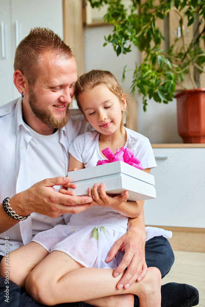 Smiling Father and Daughter Sharing a Gift Box With a Pink Bow Indoors Smiling Father and Daughter Sharing a Gift Box With a Pink Bow Indoors